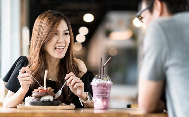 A young woman eating a big dessert with a friend