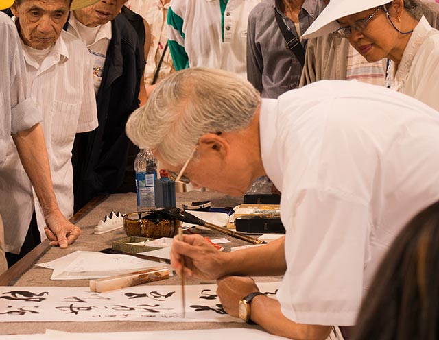 An elderly man practising chinese calligraphy with other seniors and building strong social network for better mental health
