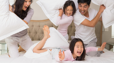 family-of-four-having-pillow-fight-on-bed.jpg